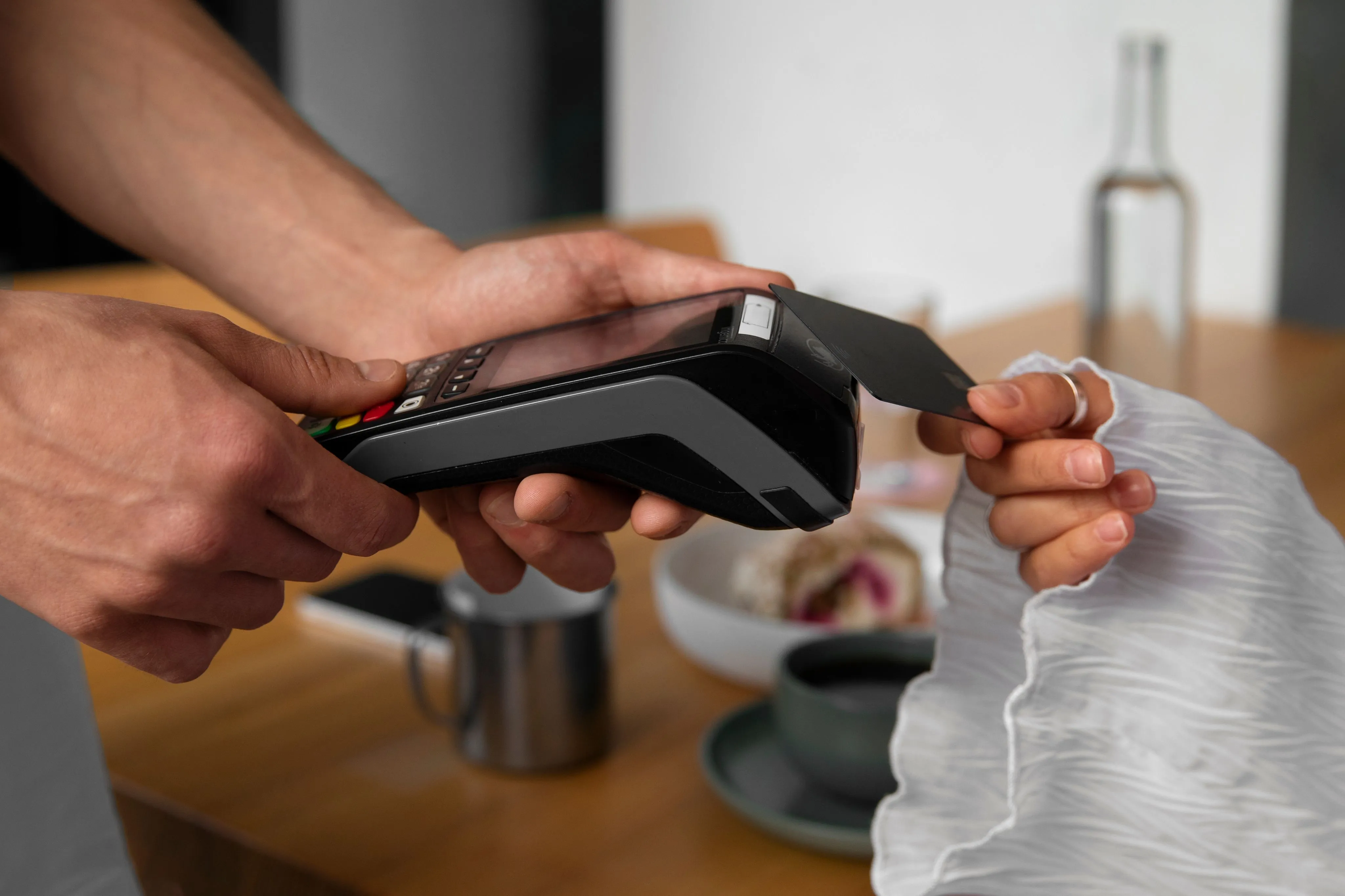 A customer tapping a bank card on a card machine in a cafe